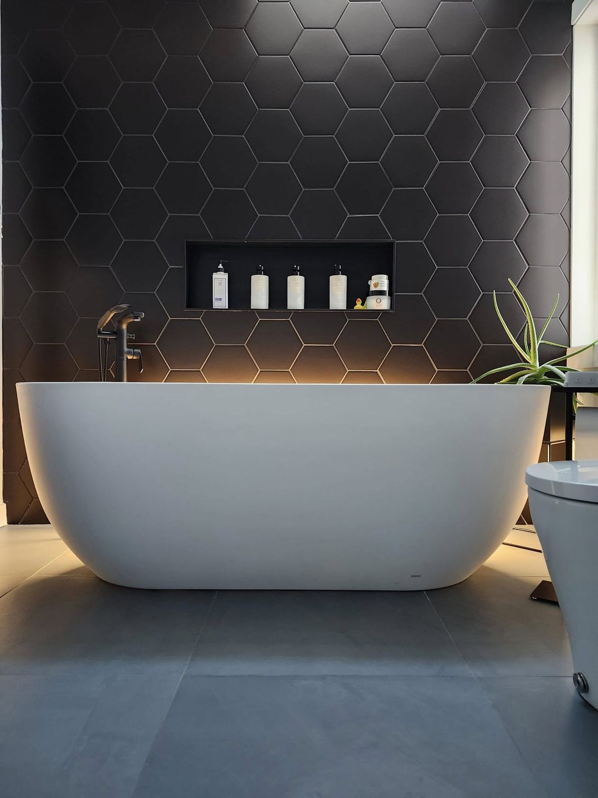 Salle de bain avec bain autoportant et mur de céramique hexagonale noire