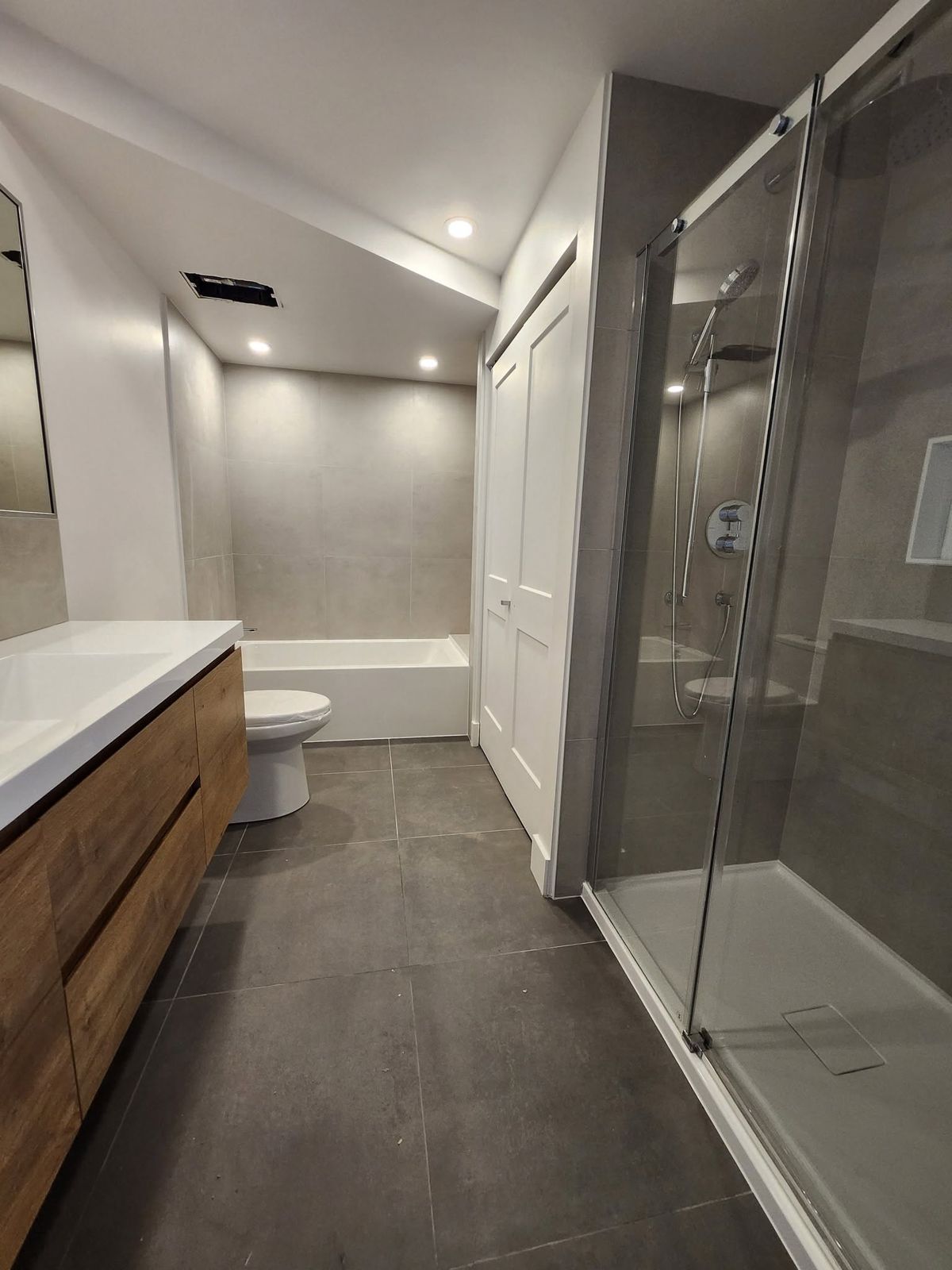 Salle de bain terminée avec douche vitrée, bain et vanité en bois