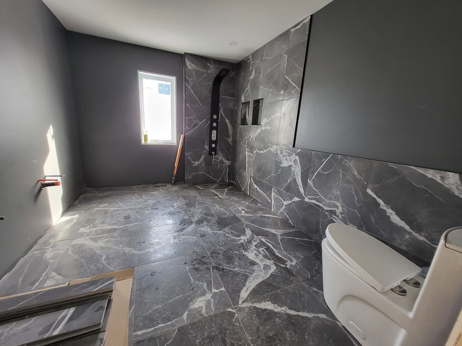 Salle de bain en céramique grise veinée avec douche ouverte